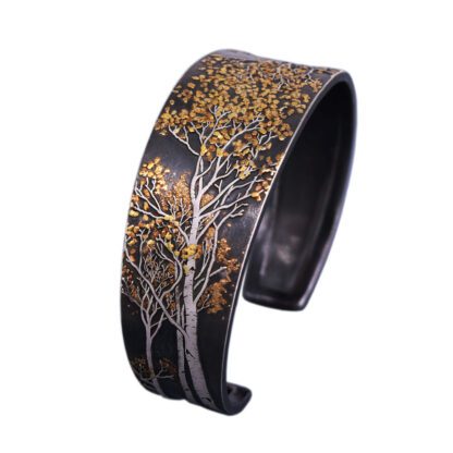 A black and gold bracelet with trees on it