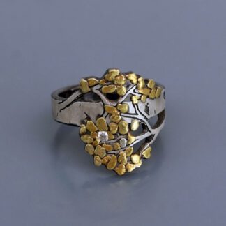 A silver ring with gold leaves on it.