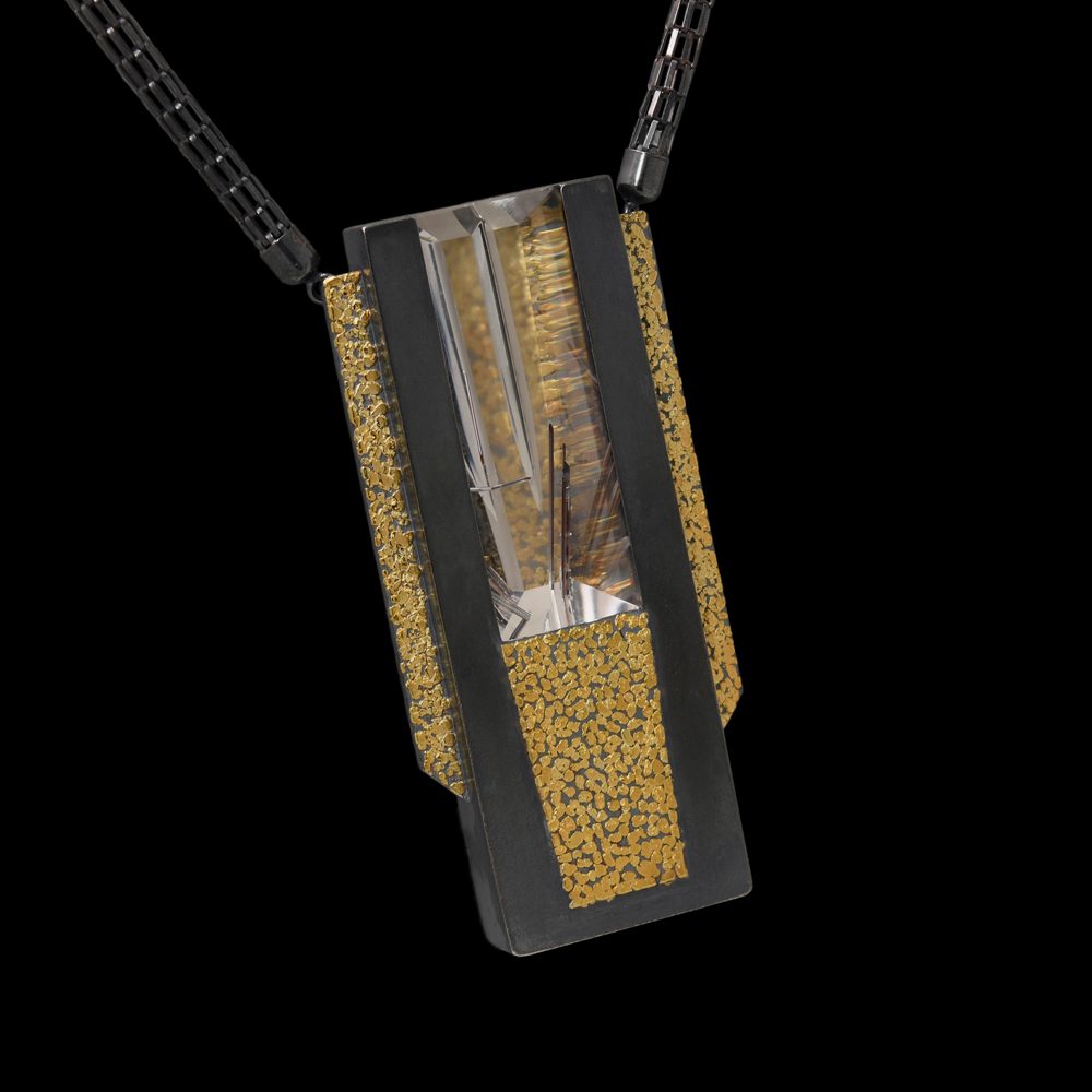 A black and gold pendant with a glass on it.