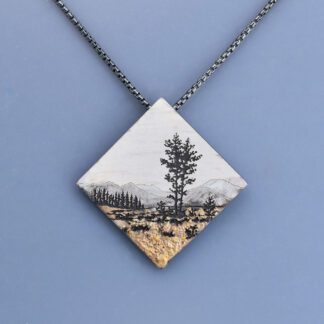 A necklace with a picture of trees and mountains