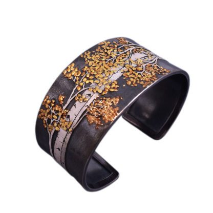A black and gold cuff bracelet with trees.
