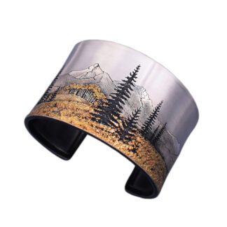 A metal cuff bracelet with trees and mountains.
