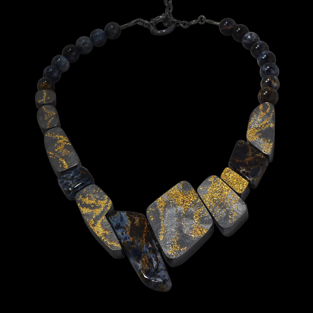 A necklace of different colored stones on a black background