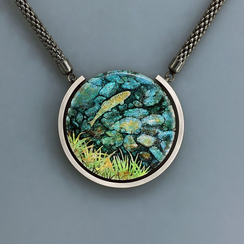 A necklace with a picture of rocks and grass.