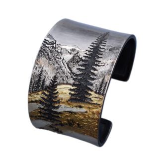 A cuff bracelet with a painting of trees and mountains.