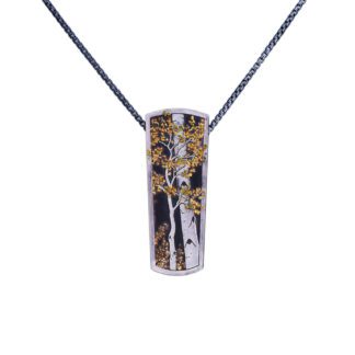 A silver pendant with gold leaf on it.