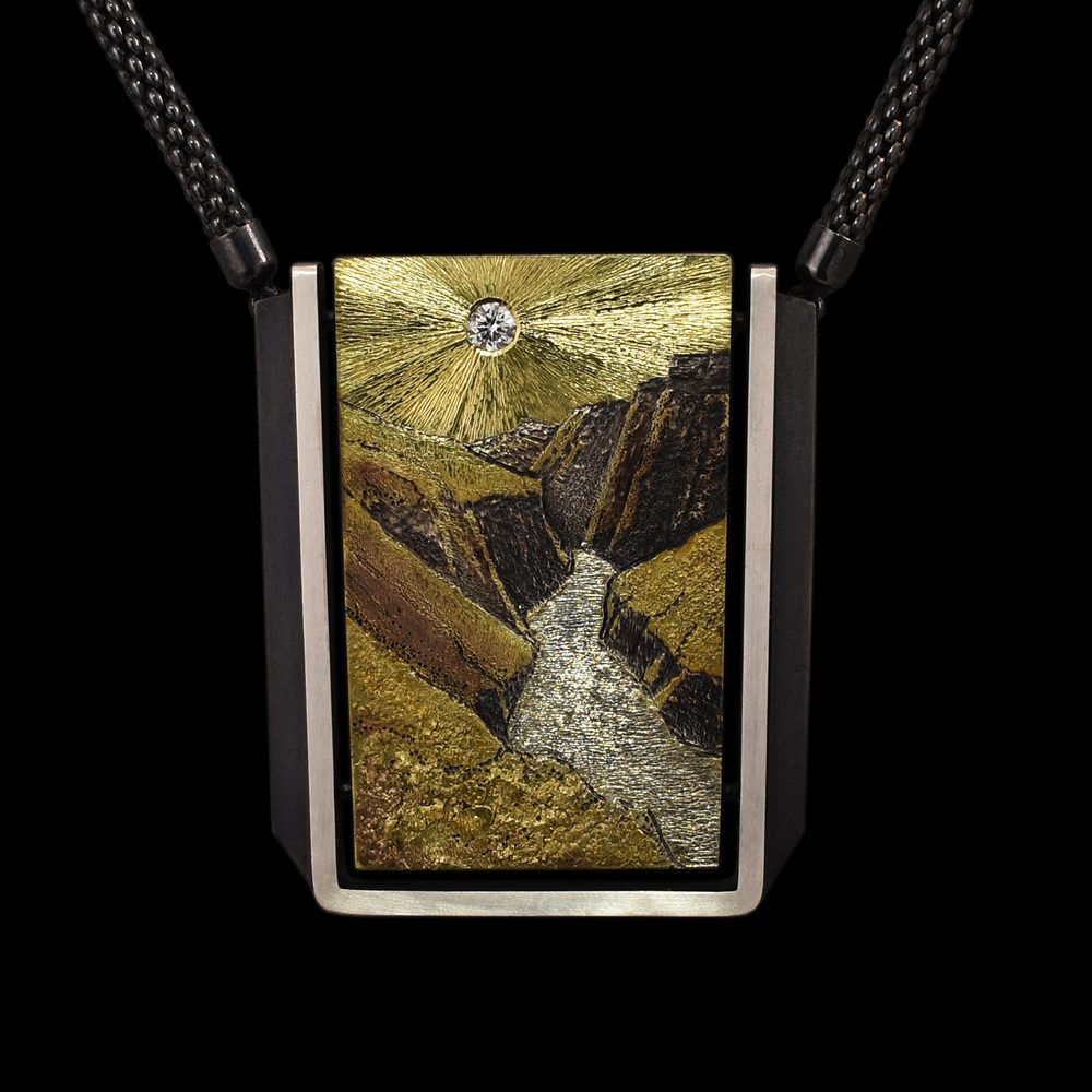 A rectangular pendant with a picture of a river and mountains.