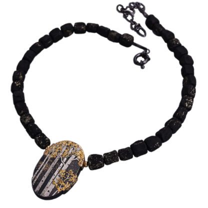 A necklace with black beads and a gold and silver pendant.