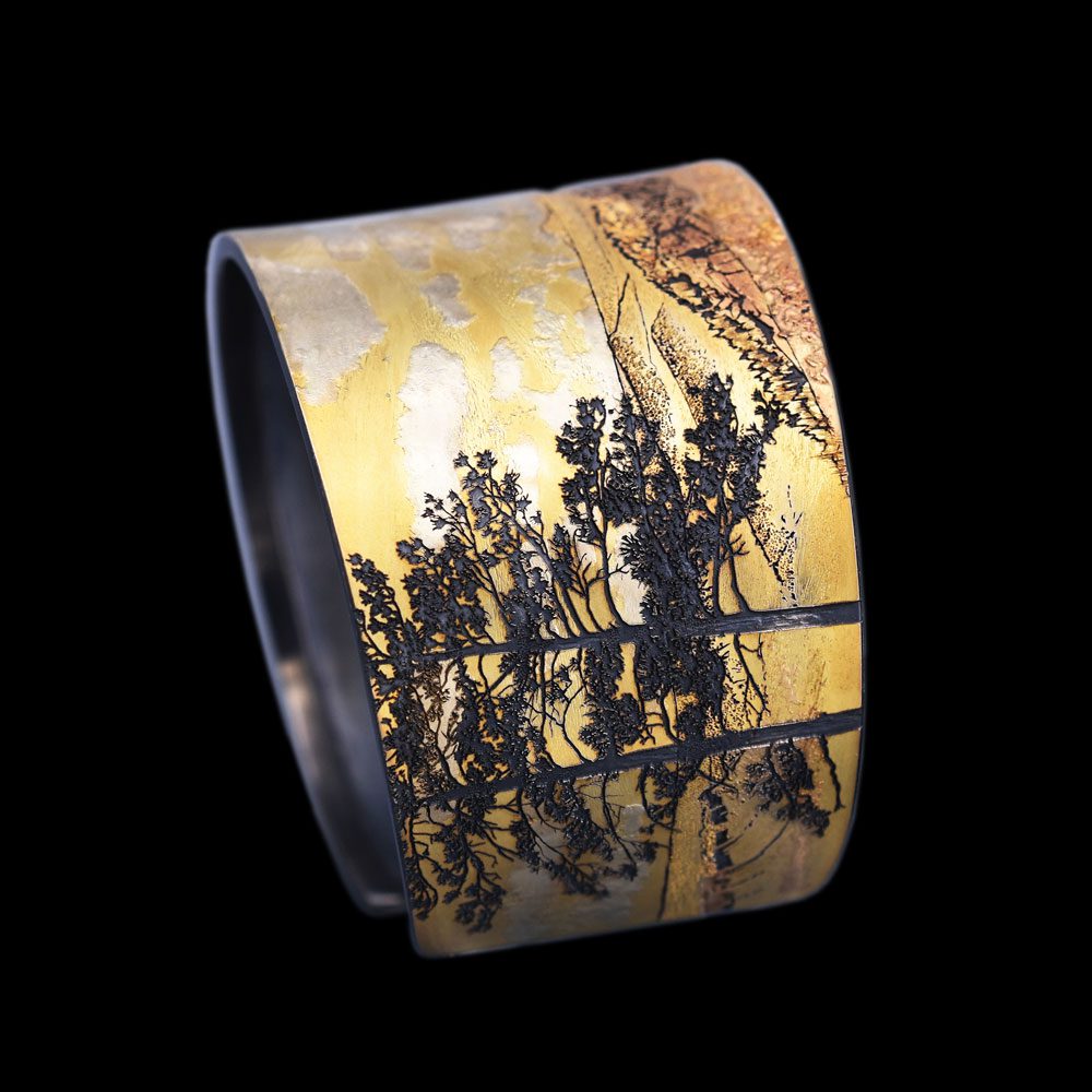 A close up of a cuff bracelet with trees