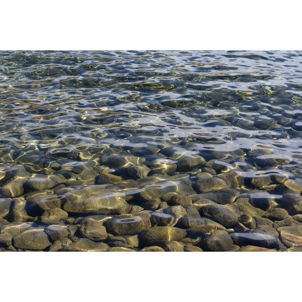 A body of water with rocks in the middle.