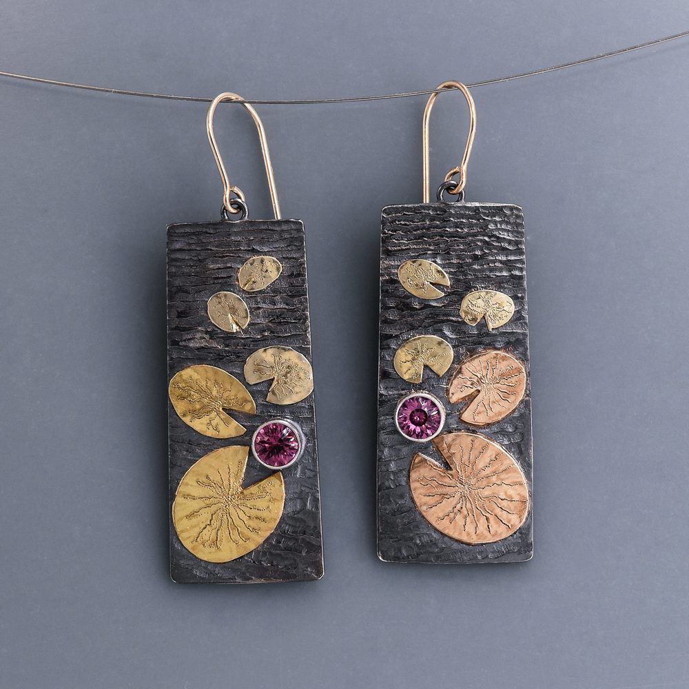 A pair of earrings with gold and silver leaves.
