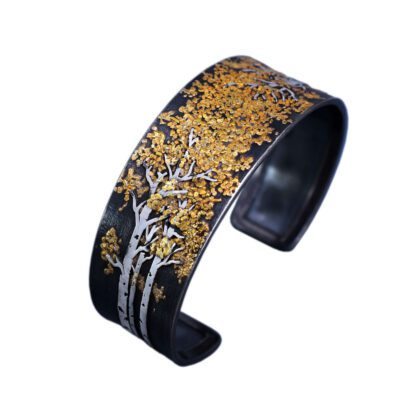 A black and gold cuff bracelet with trees.