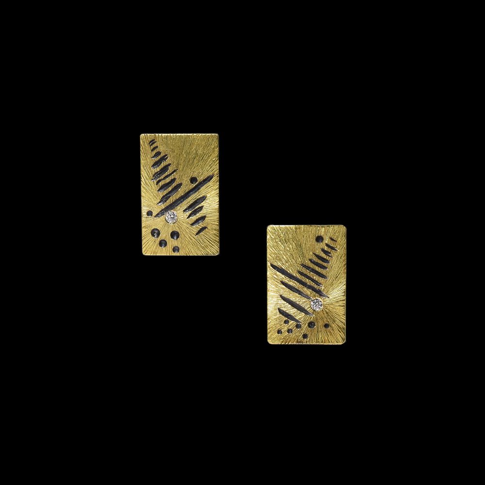 A pair of gold earrings with black design.