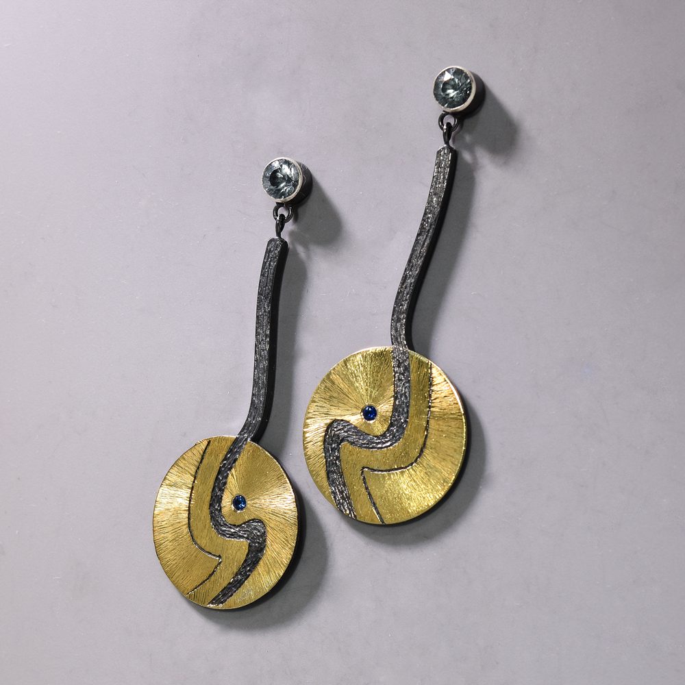 A pair of earrings with gold and black metal.