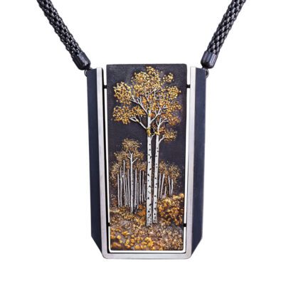 A necklace with a painting of trees on it.
