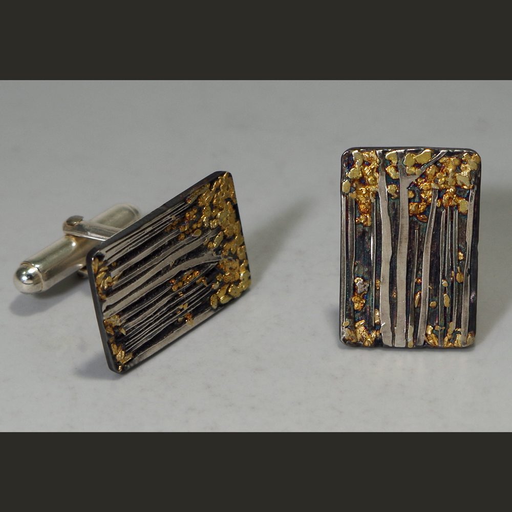 A pair of cufflinks with gold and black paint.