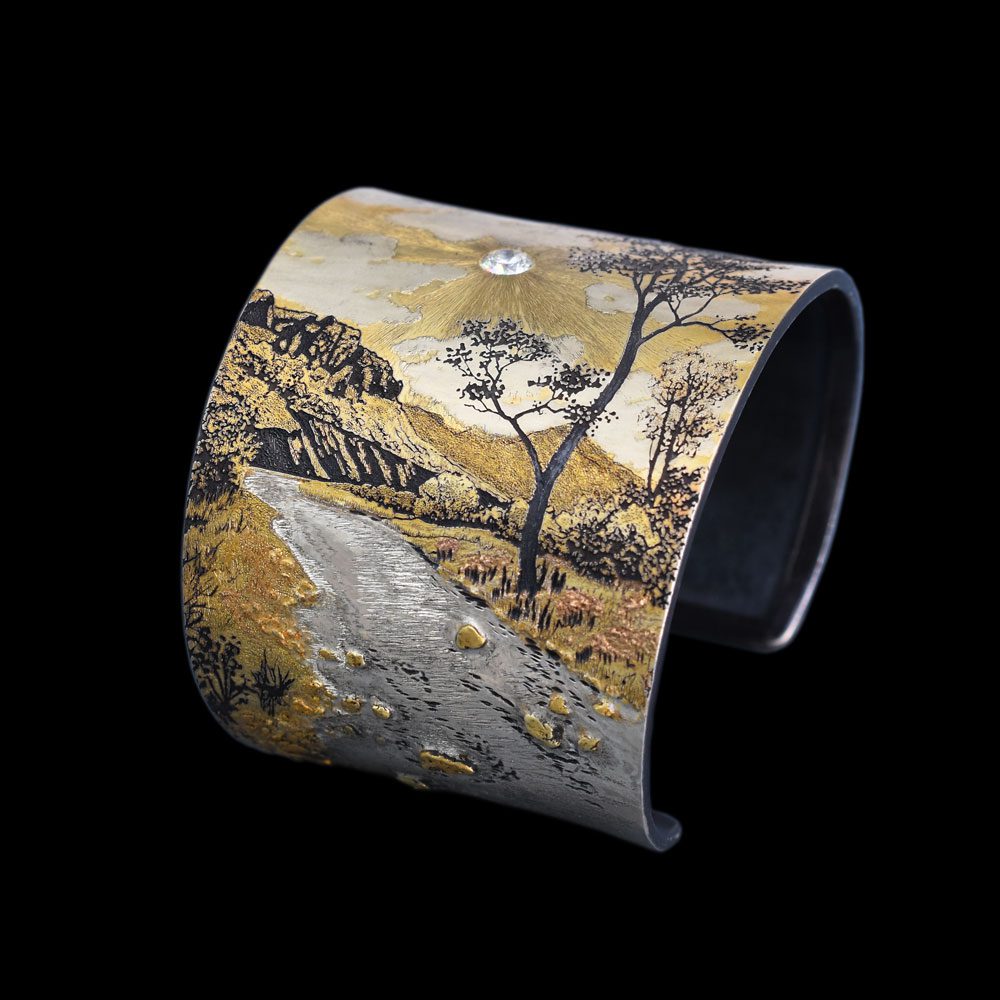 A cuff bracelet with an image of trees and water.