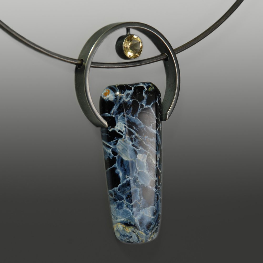 A blue and white glass pendant on a black cord.