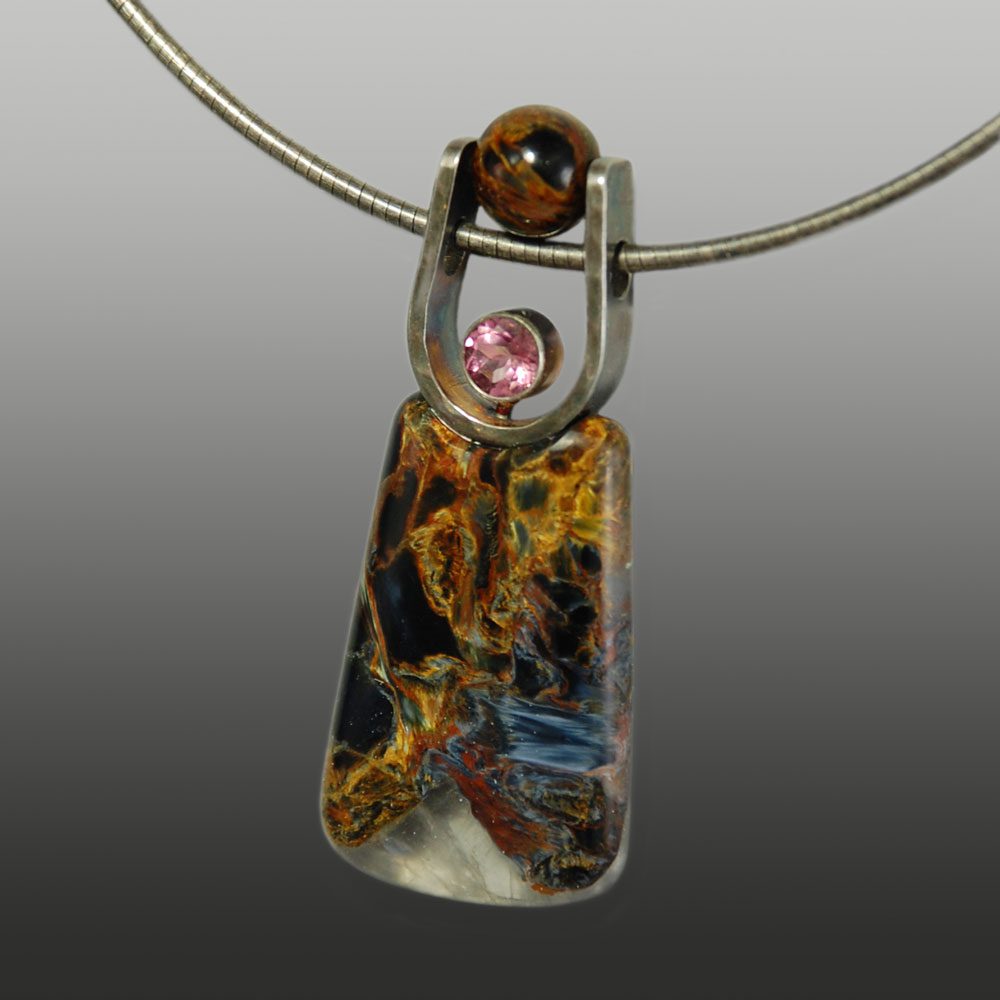 A necklace with a colorful glass pendant and a pink stone.