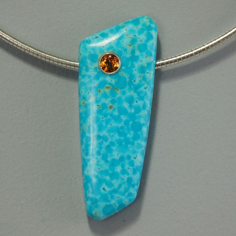 A blue stone is on a silver chain.