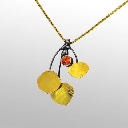A yellow necklace with three leaves and an orange stone.