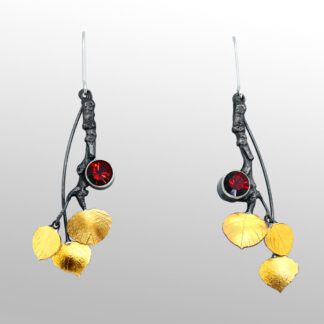 A pair of earrings with gold leaves and red stone.