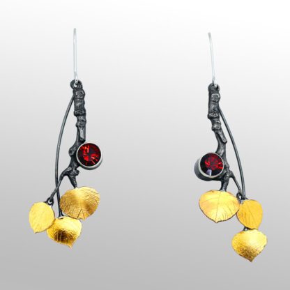 A pair of earrings with gold leaves and red stone.